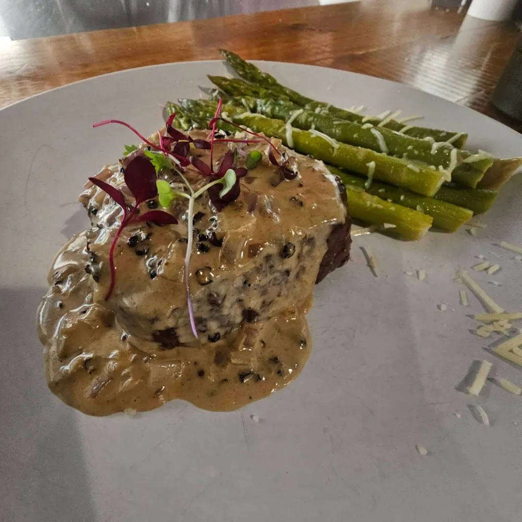 Steak topped with peppercorn sauce and asparagus